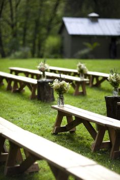 a row of wooden benches sitting on top of a lush green field