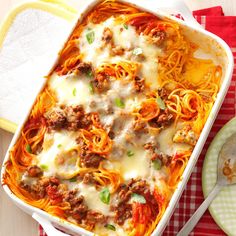 a casserole dish with meat, cheese and noodles on a checkered table cloth