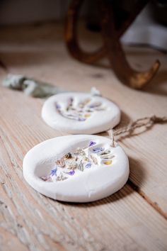 two white ceramic plates with flowers on them sitting on a table next to a pair of scissors