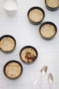 four small black bowls filled with chocolate chip muffins on top of a table