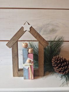 a nativity scene made out of wood and pine cones on a mantel shelf