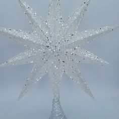 a clear glass christmas tree topper with sparkling stars on it's sides and bottom