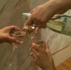 three people are toasting with wine glasses in front of them on a marble counter top