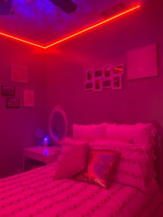 a bed in a room with pink lights on the ceiling and pictures on the wall