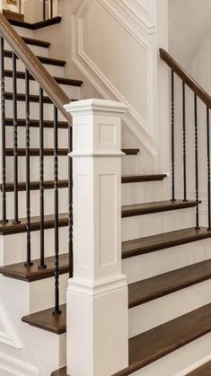 a white staircase with black railing and wood handrail