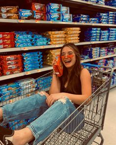 a woman sitting in a shopping cart with her face painted like an orange and smiling