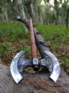 two large axes sitting on top of a log in the woods