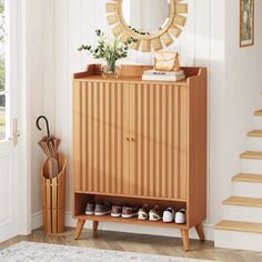 a wooden cabinet with shoes and umbrellas on it next to a stair case in a white room