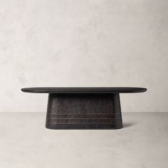 an oval shaped table with a wooden base and black wood grained finish on the top