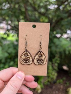 a pair of earrings with an evil eye on the front and side of it, in brown