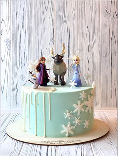 a frozen princess cake with figurines on top and snowflakes around it