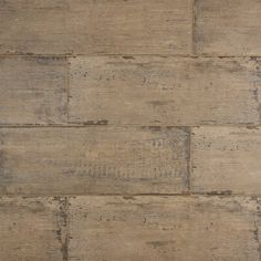 a close up view of an old wood floor textured with grey paint and brown grouting