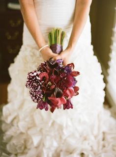 a bride holding a bouquet of red and purple flowers on her wedding day at the hotel