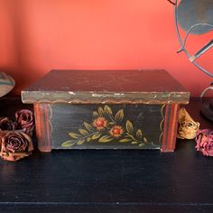 an old wooden box sitting on top of a table next to some flowers and a lamp