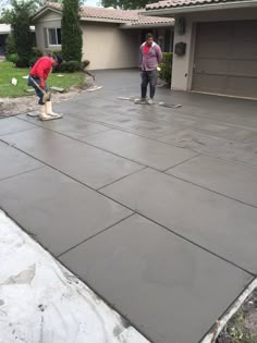 two men working on a driveway in front of a house