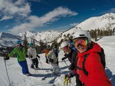 a group of people riding skis on top of a snow covered slope with mountains in the background