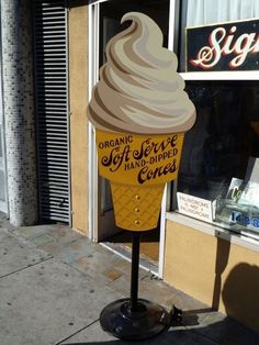 an ice cream cone is on the sidewalk in front of a sign for a coffee shop