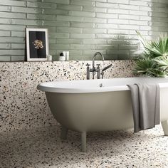 a bath tub sitting next to a plant in a bathroom