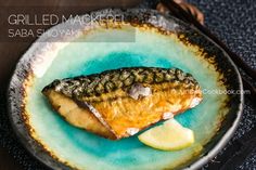 grilled mackerel on a blue plate with lemon wedges