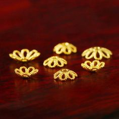 five gold earrings sitting on top of a wooden table