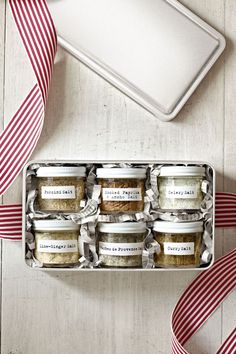 an open box filled with different types of food on top of a wooden table next to a red and white ribbon