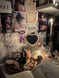 a table topped with lots of assorted items next to a wall covered in posters