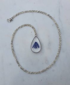 This listing is for a real bluebell stem handpicked and pressed from my garden containing 2 flower heads.  This is set in resin inside a tear drop shaped silver effect bezel pendant on a 24" silver plated chain.This necklace is so beautiful and one of a kind. It would make the perfect gift for someone special.  Please note there are tiny bubbles in the resin as you can see in the photos.Please visit my shop to see all the other types of pressed flower necklaces for sale. Silver Drop Jewelry For Mother's Day, Nickel-free Teardrop Pendant Jewelry Gift, Silver Pressed Flowers Jewelry For Memorial, Silver Pressed Flowers Memorial Jewelry, Blue Jewelry With Pressed Flowers For Mother's Day, Drop Necklace With Natural Inclusions For Gifts, Handmade Teardrop Jewelry For Mother's Day, Dainty Silver Drop Necklace Gift, Silver Memorial Jewelry With Pressed Flowers