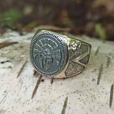 a silver ring with an image of jesus on it sitting on top of a rock