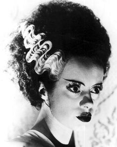 a black and white photo of a woman with curly hair wearing an elaborate hairstyle