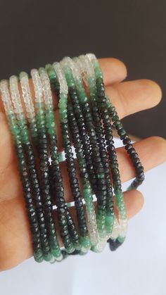 a hand holding several beads with green and white designs on them, all stacked together