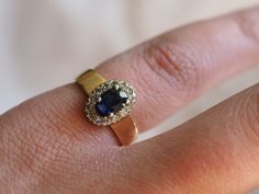 a woman's hand with a ring on it that has a blue stone in the middle