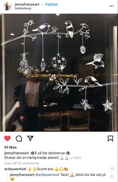 a man standing in front of a window with christmas decorations on the windowsills