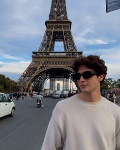 a man standing in front of the eiffel tower with sunglasses on his head