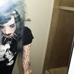 a woman with black hair and piercings standing in front of a mirror