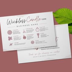 two business cards sitting next to each other on top of a pink surface with green leaves