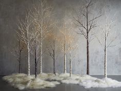 four trees with white fur in front of a concrete wall and grey floor, one has no leaves on it