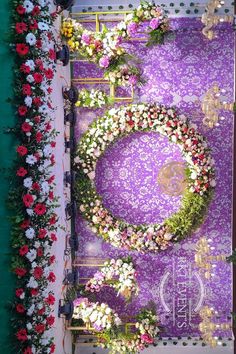 an overhead view of a purple carpet with flowers and greenery on it in front of a green wall