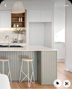 a kitchen with two stools in front of an island