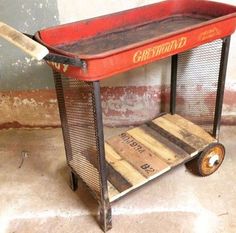 a red cart sitting on top of a floor next to a wall