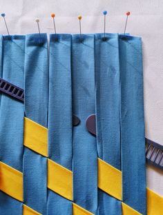 a piece of blue fabric with yellow strips and pins on it