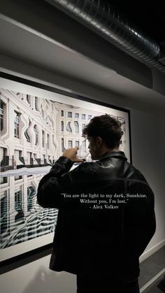 a man standing in front of a painting with a quote written on the back of it