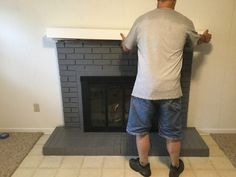 a man standing in front of a fire place with his hands on the fireplace's mantle