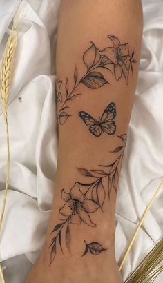 a woman's foot with a butterfly and flowers tattoo on the side of her leg