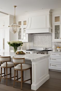 a kitchen with white cabinets and an island in the middle, surrounded by stools