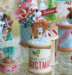 small christmas trees and reindeer figurines sitting on a table with tinsels