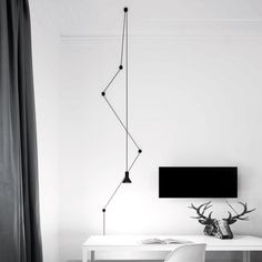 a black and white photo of a room with a desk, chair, lamp and television