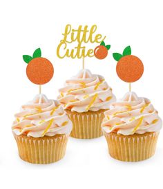 three cupcakes with white frosting and orange toppers on them, each topped with a little cutie