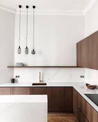 a kitchen with wooden cabinets and white counter tops, two hanging lights above the sink