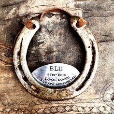 an old horseshoe hanging on the side of a wooden wall with a plaque in it