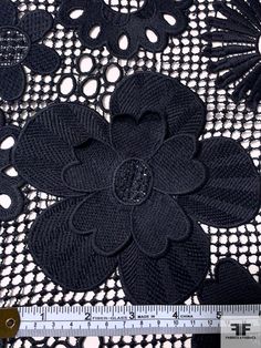 a black lace with flowers on it next to a ruler